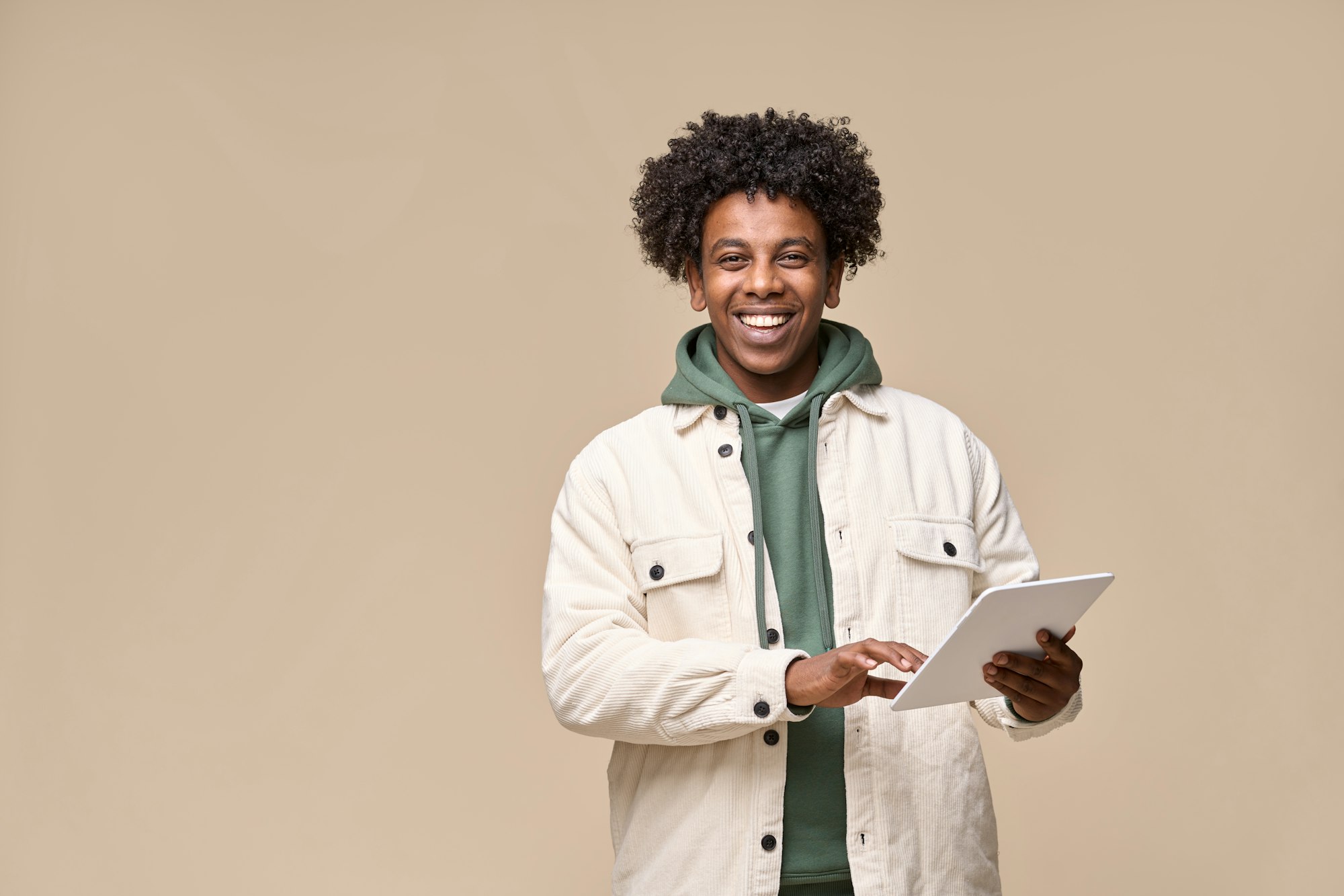 Happy African American guy using tablet isolated on beige background.
