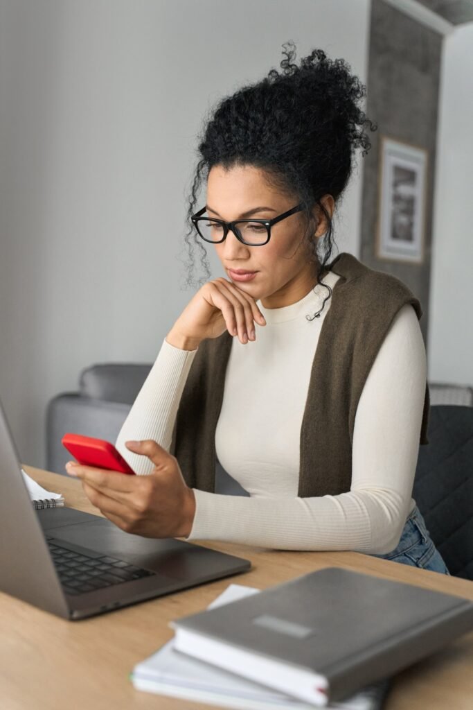 young american mixed race girl sitting at desk with pc and cellphone indoors